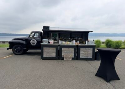 Shake & Stir vintage black bar truck and mobile bar setup with cocktail tables on the Hudson River waterfront, Irvington NY