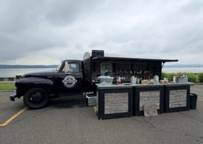 Shake & Stir vintage black bar truck with awning open showing the full bar setup on the Hudson River waterfront, Irvington NY